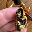 Bronze monkey keychain held by a hand with a blurred background
