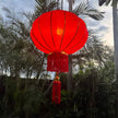 red satin Chinese lantern with gold decoration hanging in garden
