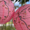 Pink paper lanterns with tree design against a blurred natural background